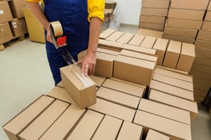 Freight and Logistics services - Warehouse worker taping a box on a pallet