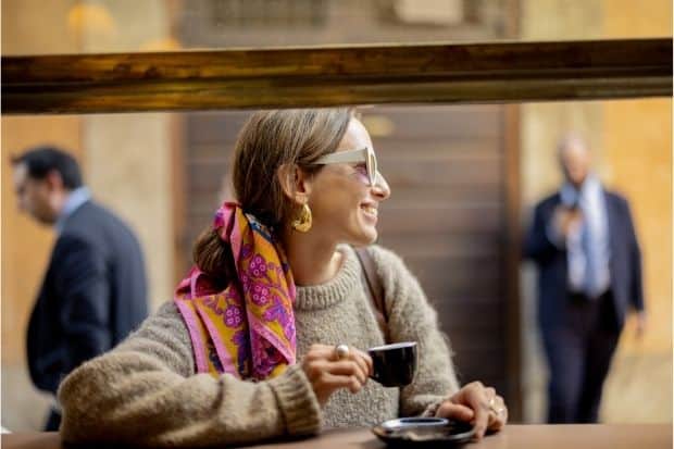 A woman at an outdoor table in Italy shows how to drink espresso