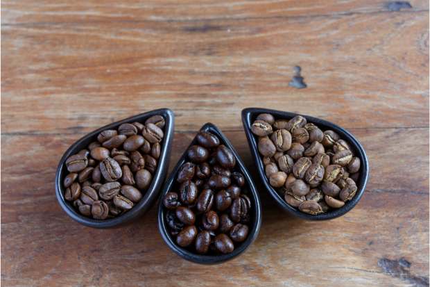 Three small dishes containing light, medium and dark coffee roasts