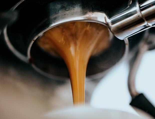 Thick stream of espresso flowing from the bottom of a portafilter