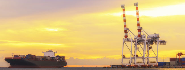 Loaded cargo ship near port shipping cranes 