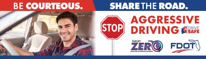 Billboard reading Be courteous. Share the road. with a smiling driver, a stop sign and the words Aggressive Driving.