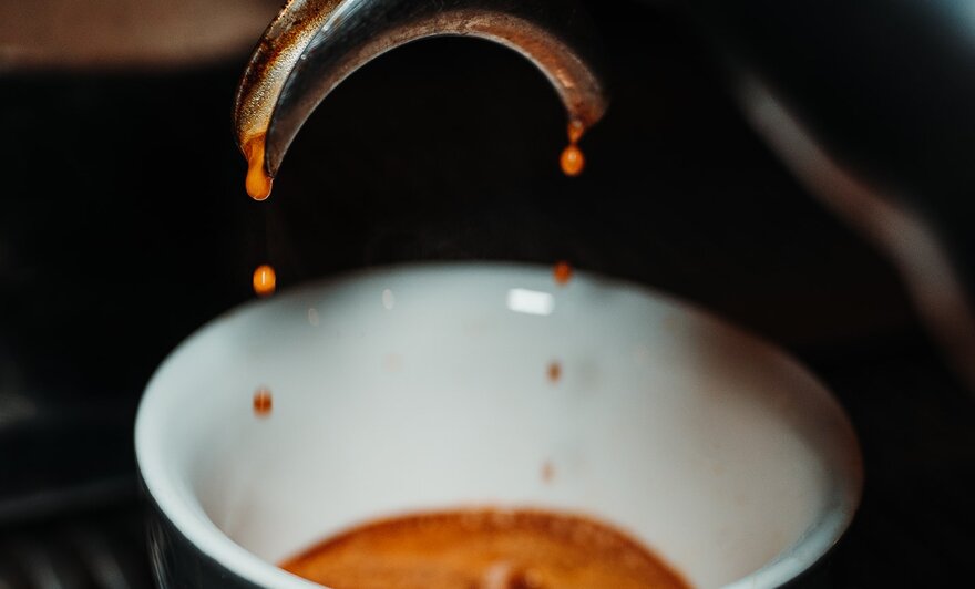 Espresso drips from the spout into the cup after passing through the portafilter