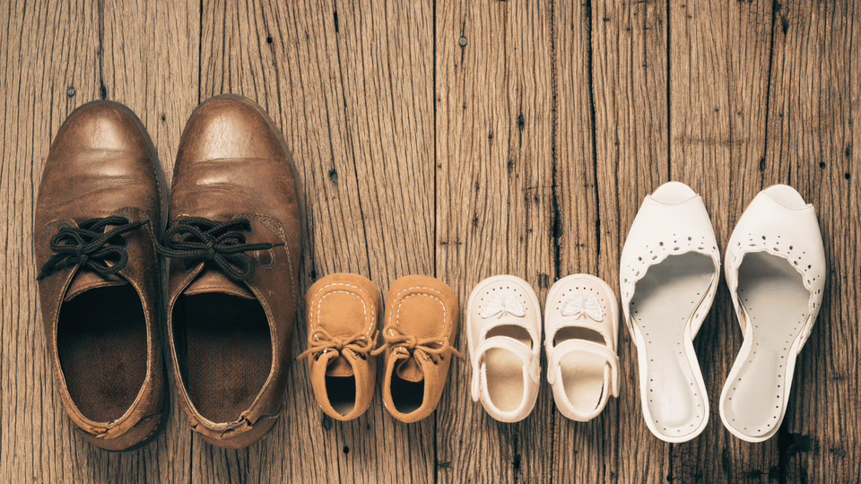 Vaterrolle braucht klare Haltung für stabile Familienbindung Braune Männerschuhe neben Kinderschuhen und Frauenschuhen als Symbol für klare Vaterrolle und familiäre Verantwortung