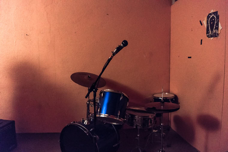 A blue drumset in front of orange walls in a basement rehearsal room in Tehran.