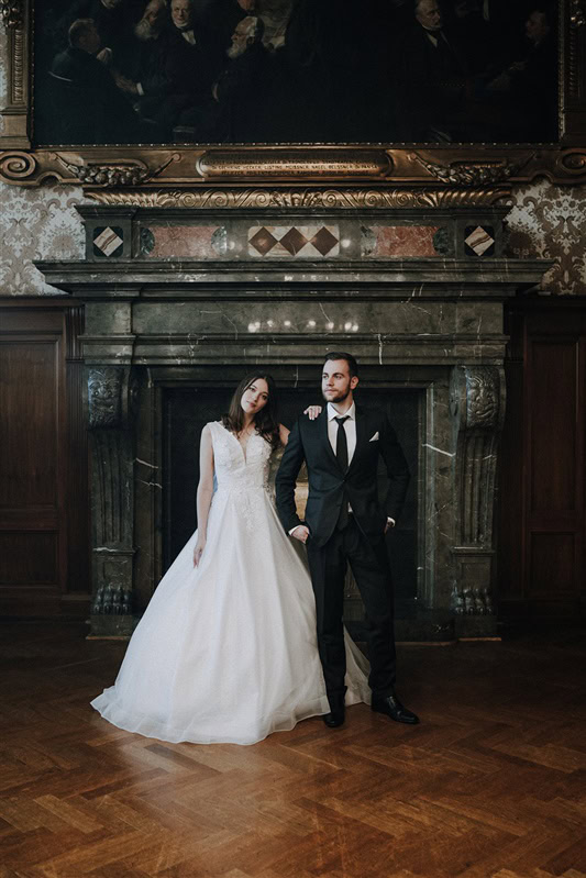 Brautpaar steht vor einem Kamin im Standesamt bei der hochzeit