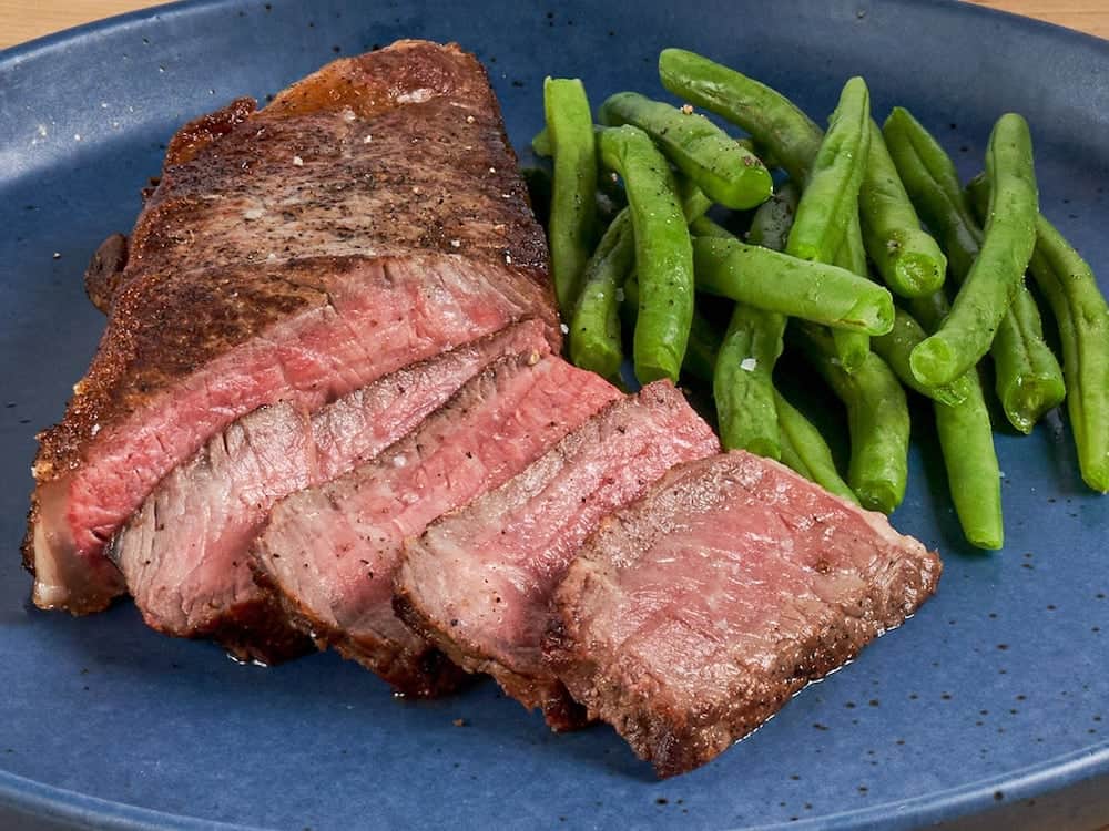 steak with green beans on a blue plate
