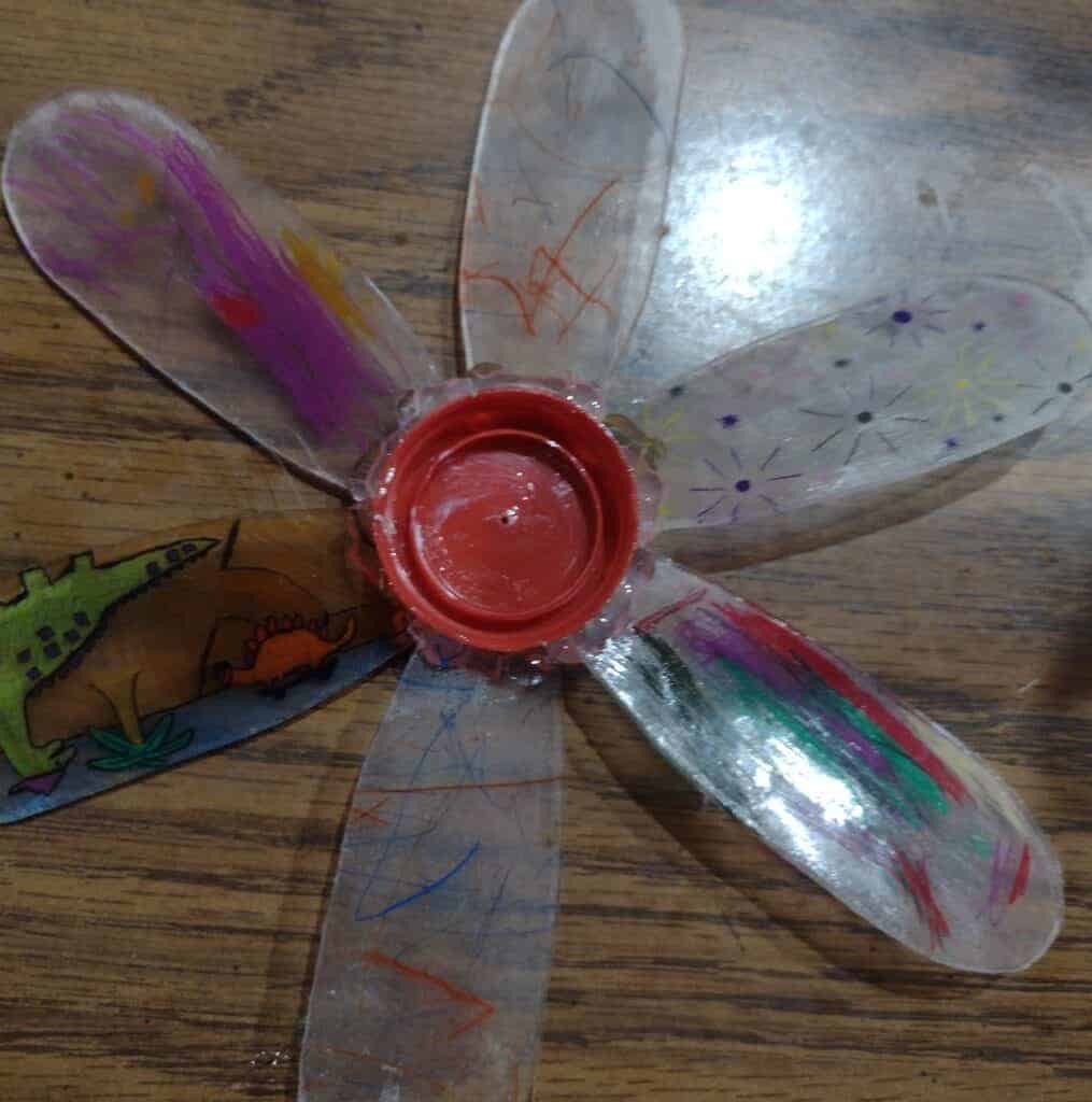 Picture of back of a DIY garden pinwheel with extra hot glue around the milk jug lid center