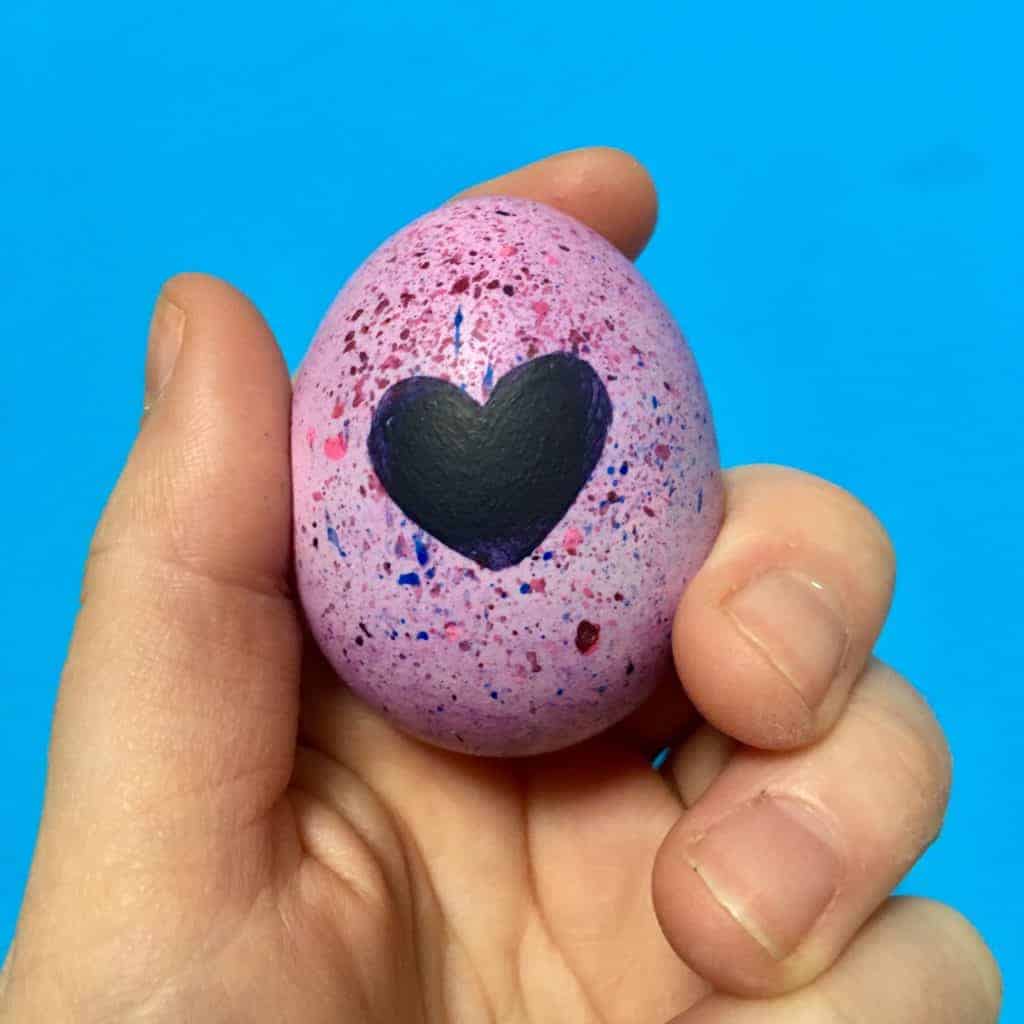 hatchimal egg being held by hand with blue wall in the background