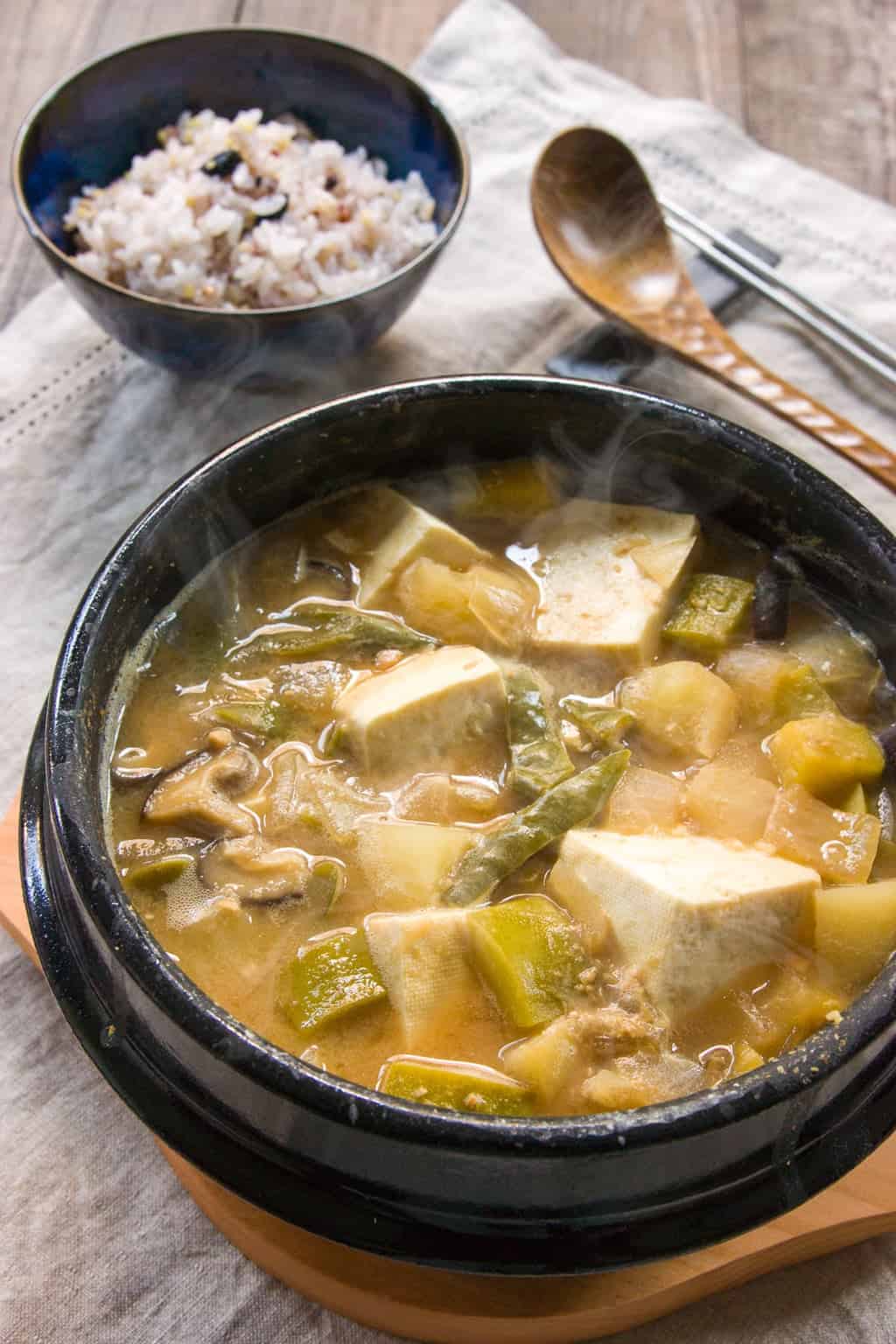 Doenjang Jjigae Recipe Doenjang Jjigae, is a hearty Korean stew loaded with vegetables, mushrooms and garlic and redolent of garlic. Seasoned with a fermented bean paste, it has an nutty funk that gives the soup a marvelous earthy flavor.