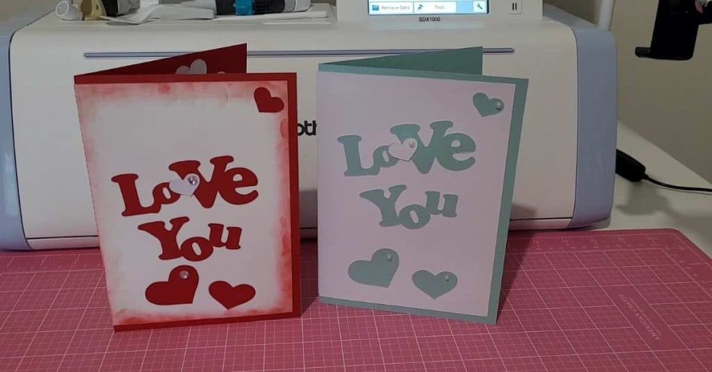 Popup heart cards with Love You on the front. One in red with white background and the other in teal blue with a white background. 