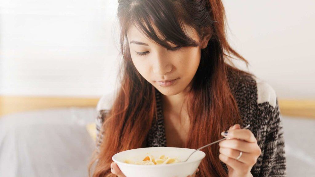 Asian woman eating soup during a rainy day