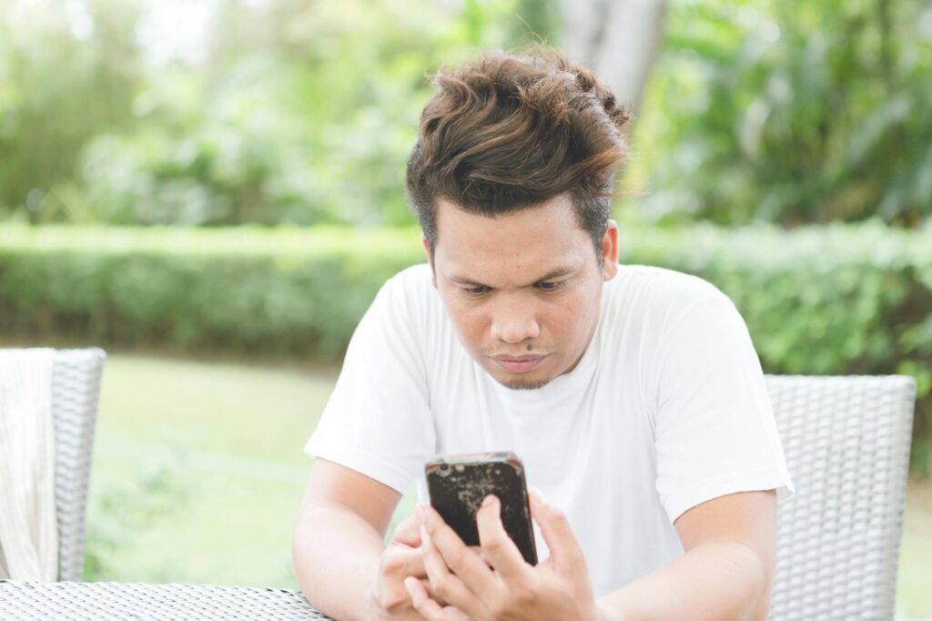 serious man using modern smartphone on terrace