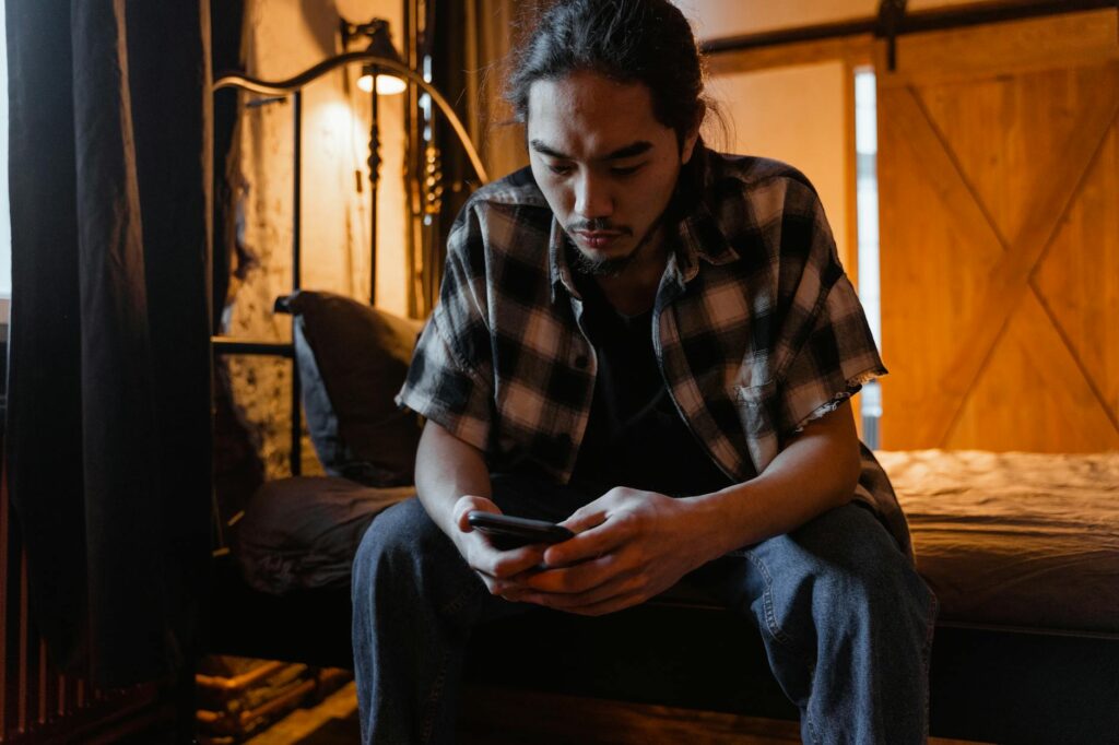 man seated on beside using phone