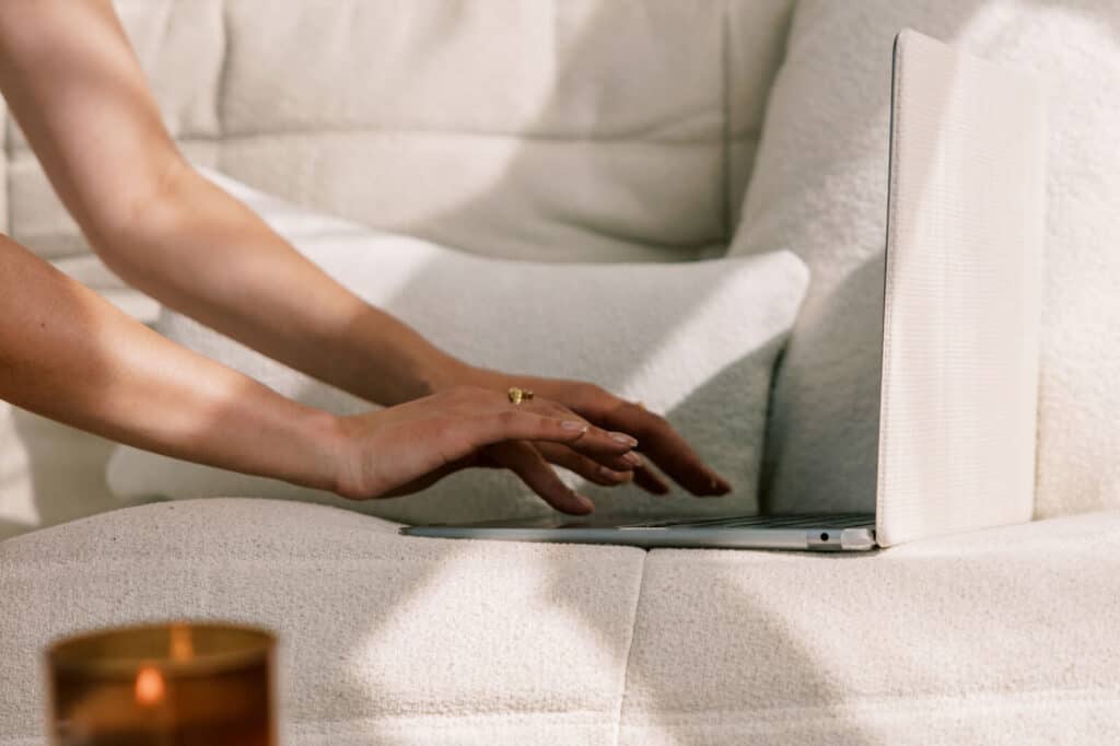 woman designing her website on a laptop while sitting on a couch