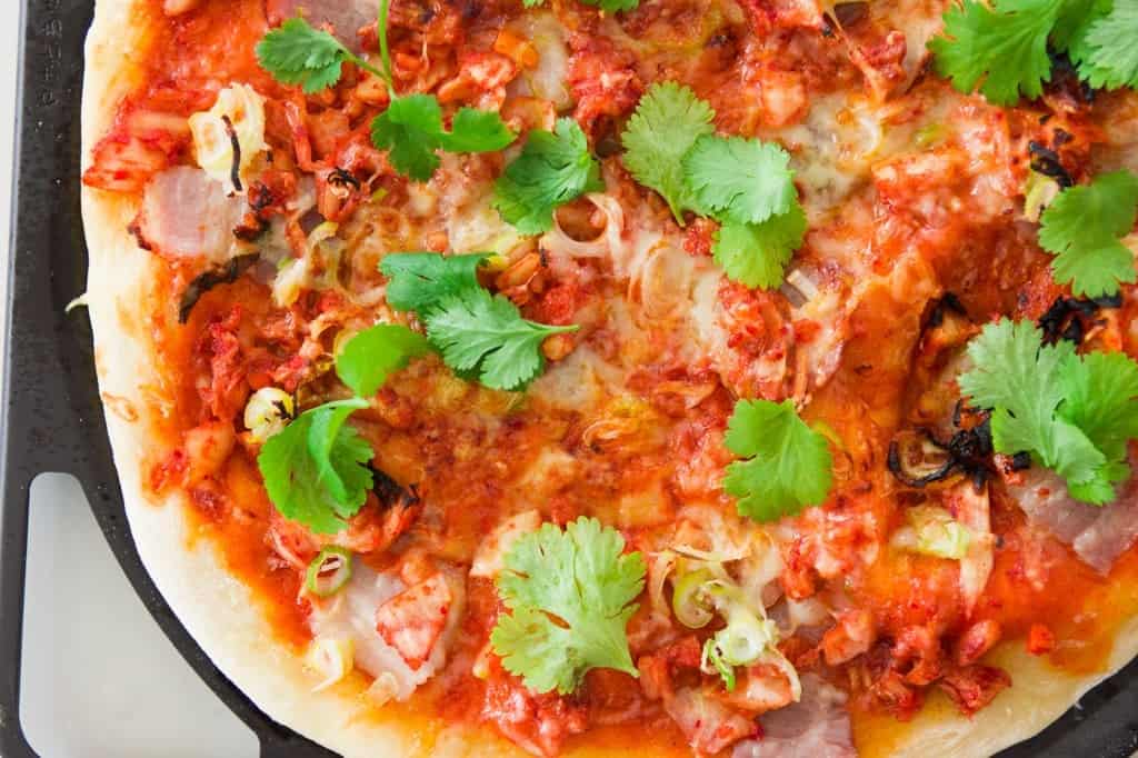 Kimchi Pork Belly Pizza Recipe Delicious grilled kimchi and pork belly pizza on top a crisp crust seasoned with spicy gochujang sauce.