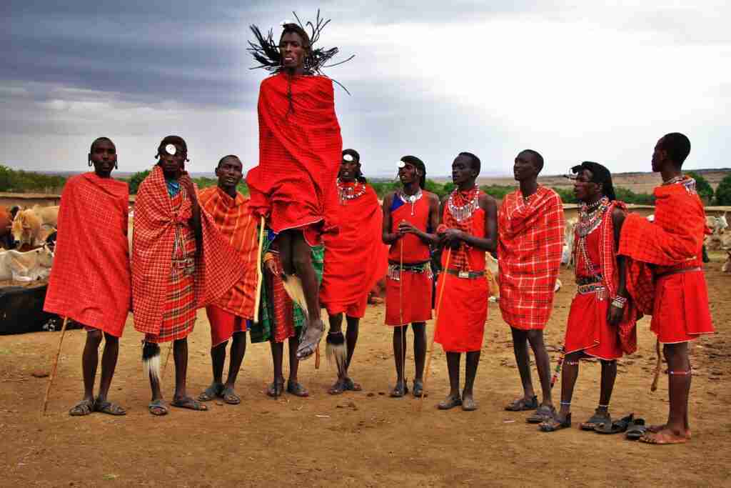 Beyond A  Romantic Wildlife Trip Group Of Men Wearing Red Suits Standing On Brown Soil