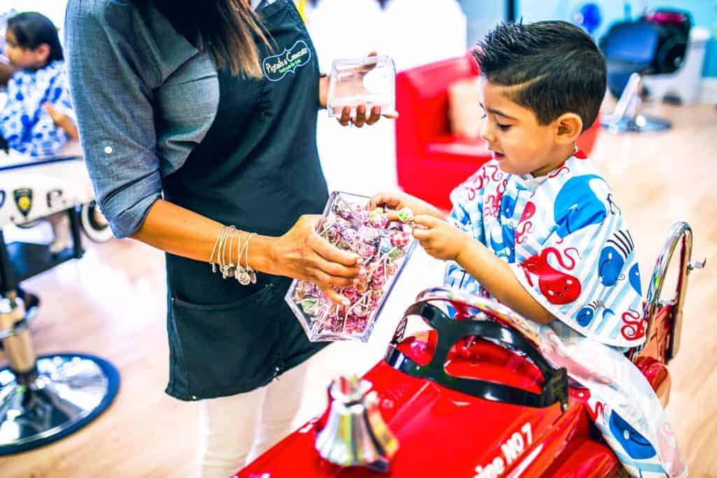 little boy choosing a lollipop after getting his hair cut at Pigtails & Crewcuts kids hair salon