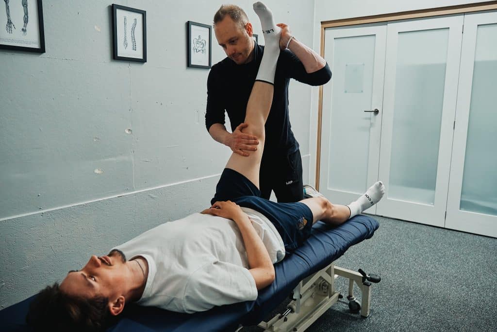 A sports therapist is performing a hamstring stretch to a patient at seventy9 Sports Therapy, a sports injury clinic in Guildford, sports therapy in Guildford, sports massage in Guildford, sports therapy clinic in Guildford, sports massage clinic in Guildford