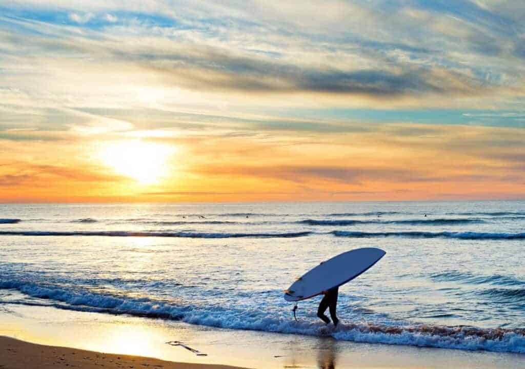 Surfer taking classes at one of the best surfing camps in Portugal in the surf with his board