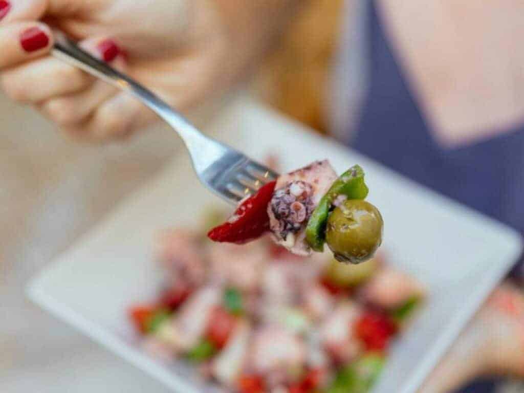 A bite of octopus salad on a fork.