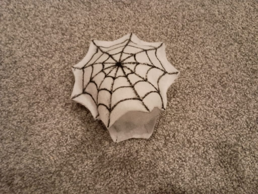 Picture of a felt spiderweb toy glued on all sides but three and filled with stuffing