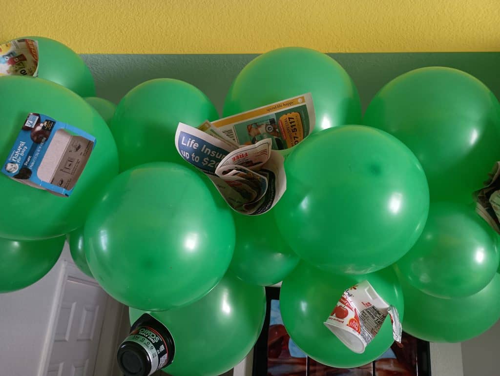 Picture of newspapers and other trash attached to a group of green balloons