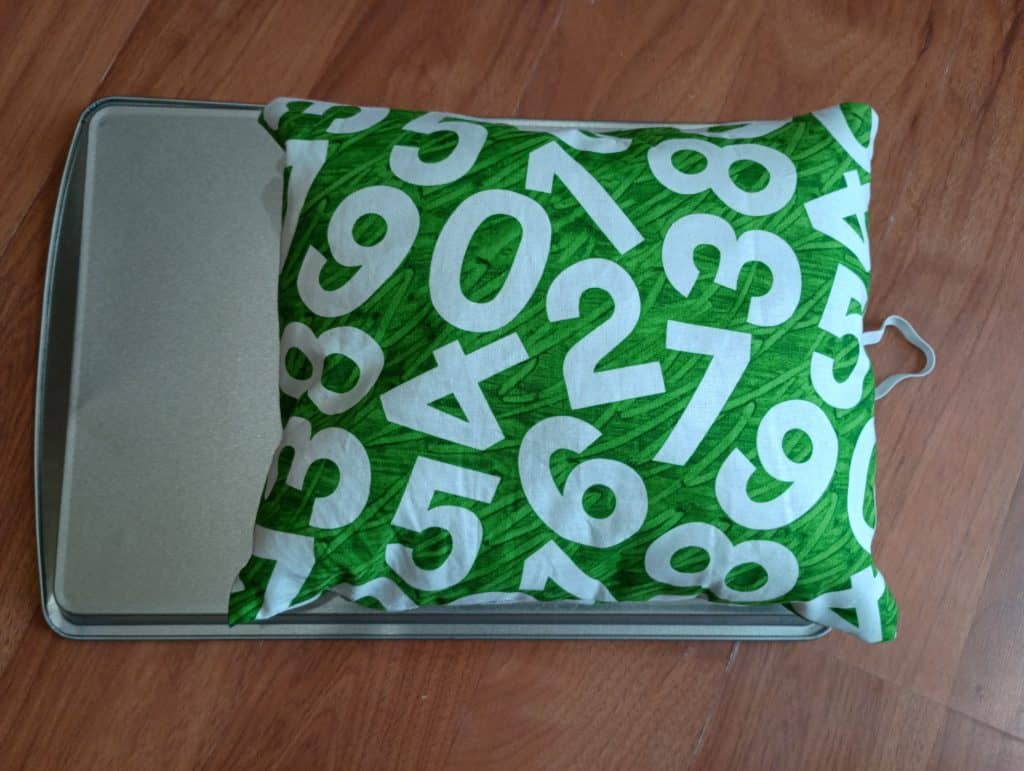 Picture of a pillow attached to a cookie sheet as a DIY car seat tray