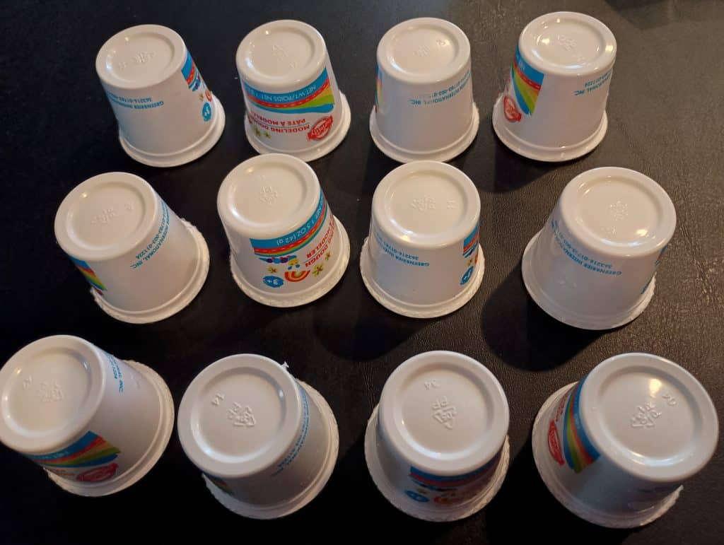 Picture of a bunch of modeling dough containers upside down on a table