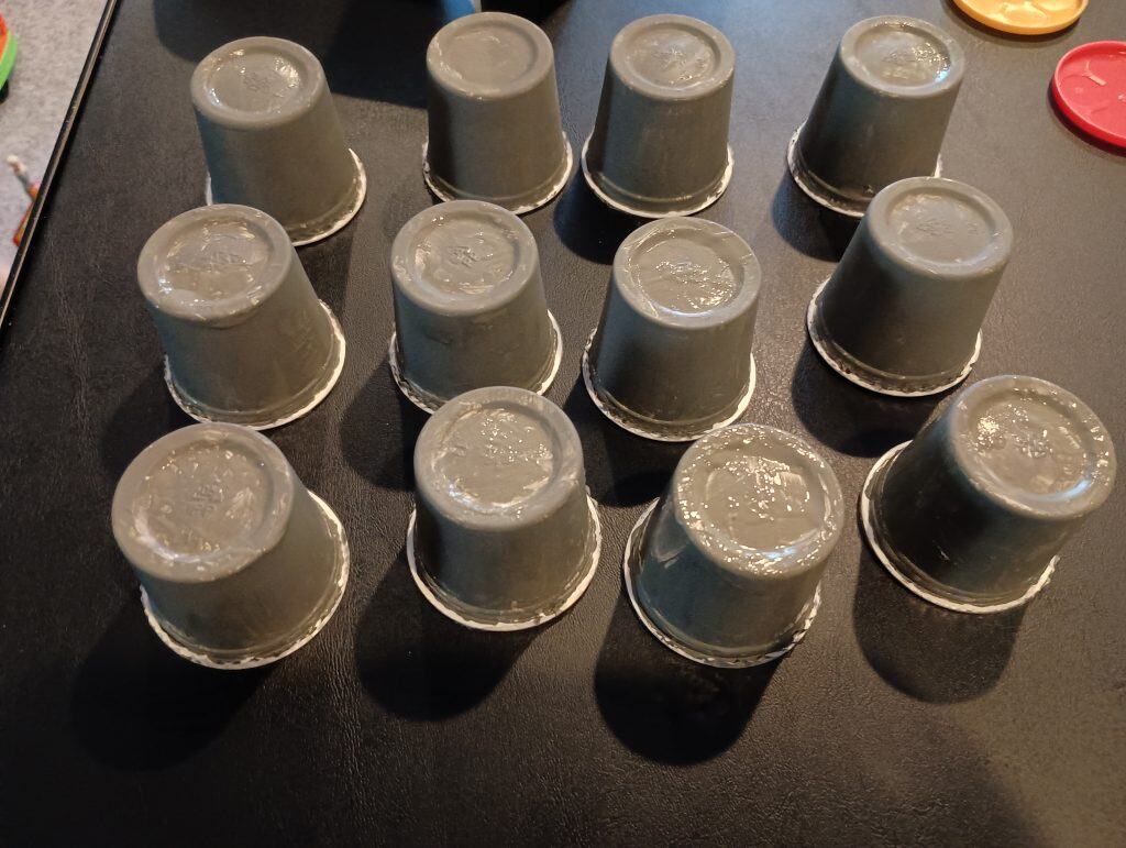 Picture of a bunch of containers of modeling dough painted grey