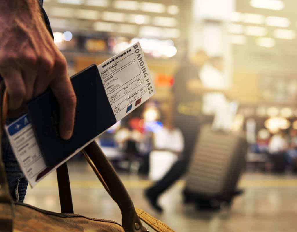 Close up of traveller holding his bording pass in his passport while walking in the airport.