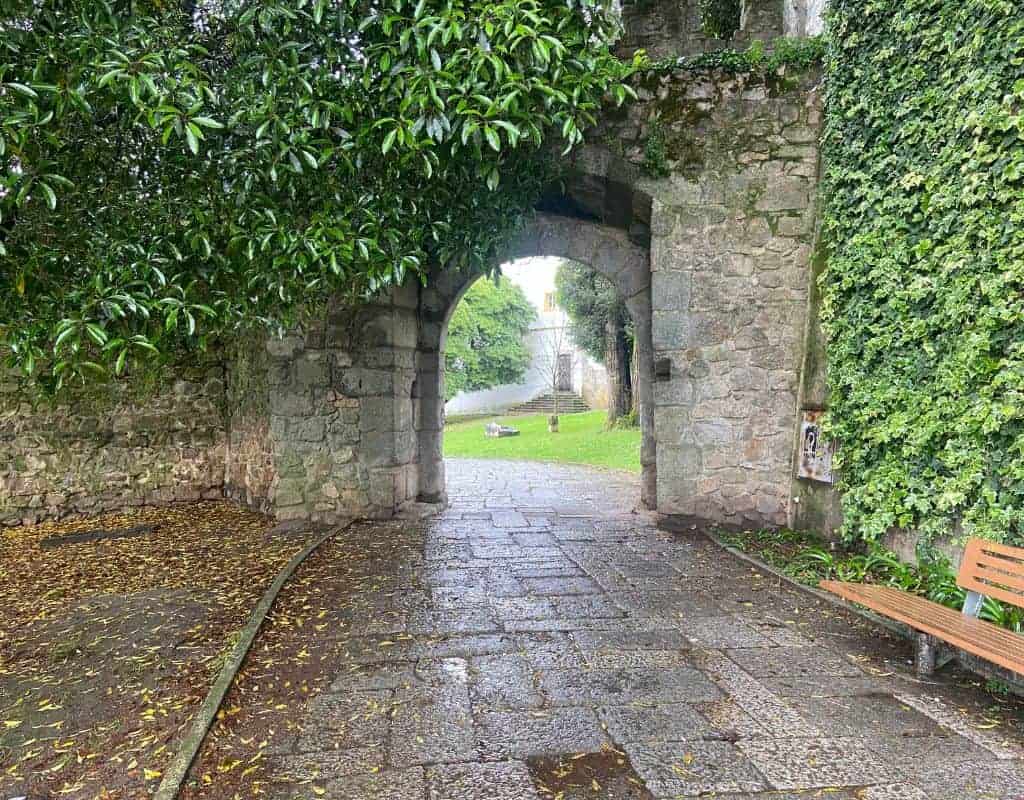 A lovely stone arch in the city walls, over a stone pathway covered in ivy in Evora old town.