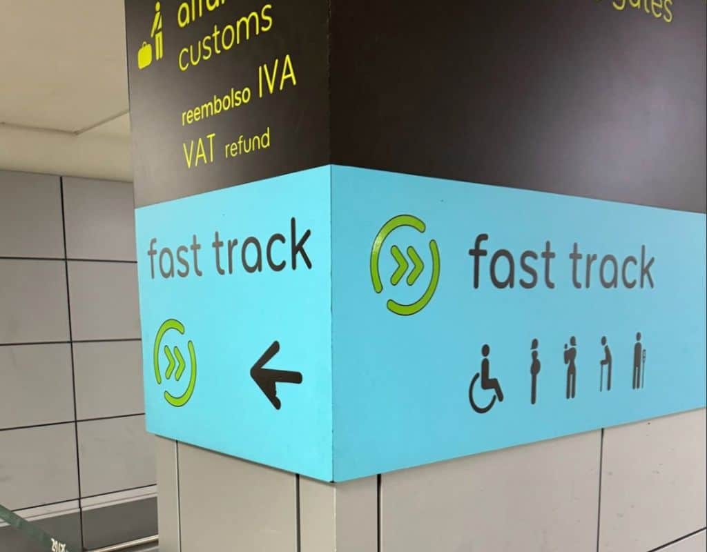 Lisbon Airport Fast Track signage in bold black and turquoise, directing travelers to customs, VAT refund, and Fast Track service for eligible passengers.