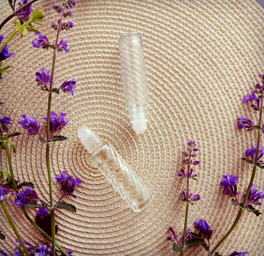 roll on perfume oils on mat surrounded by flowers