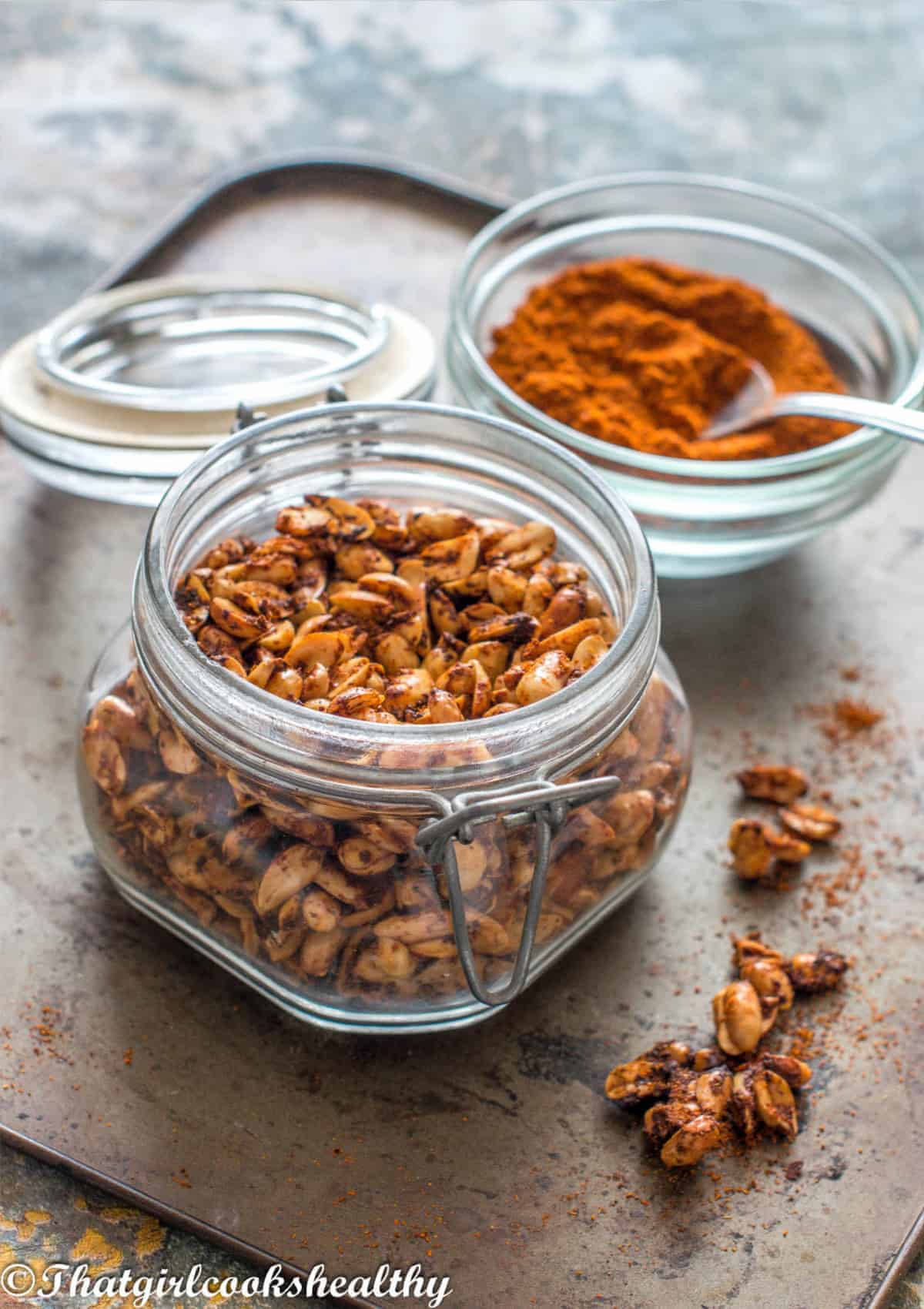 Peanuts in a jar with cayenne pepper in a small bowl