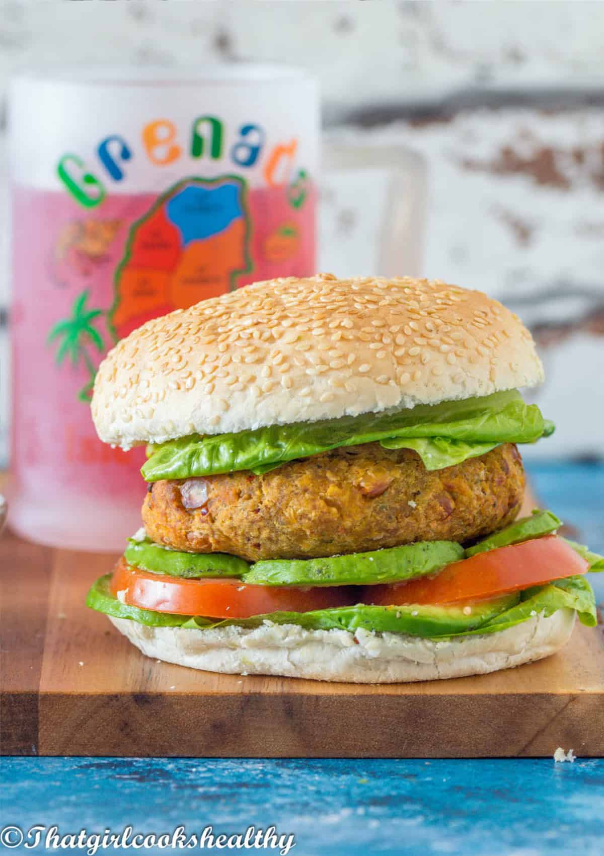 Close of the burger with lettuce, avocado and tomato in a seeded bun