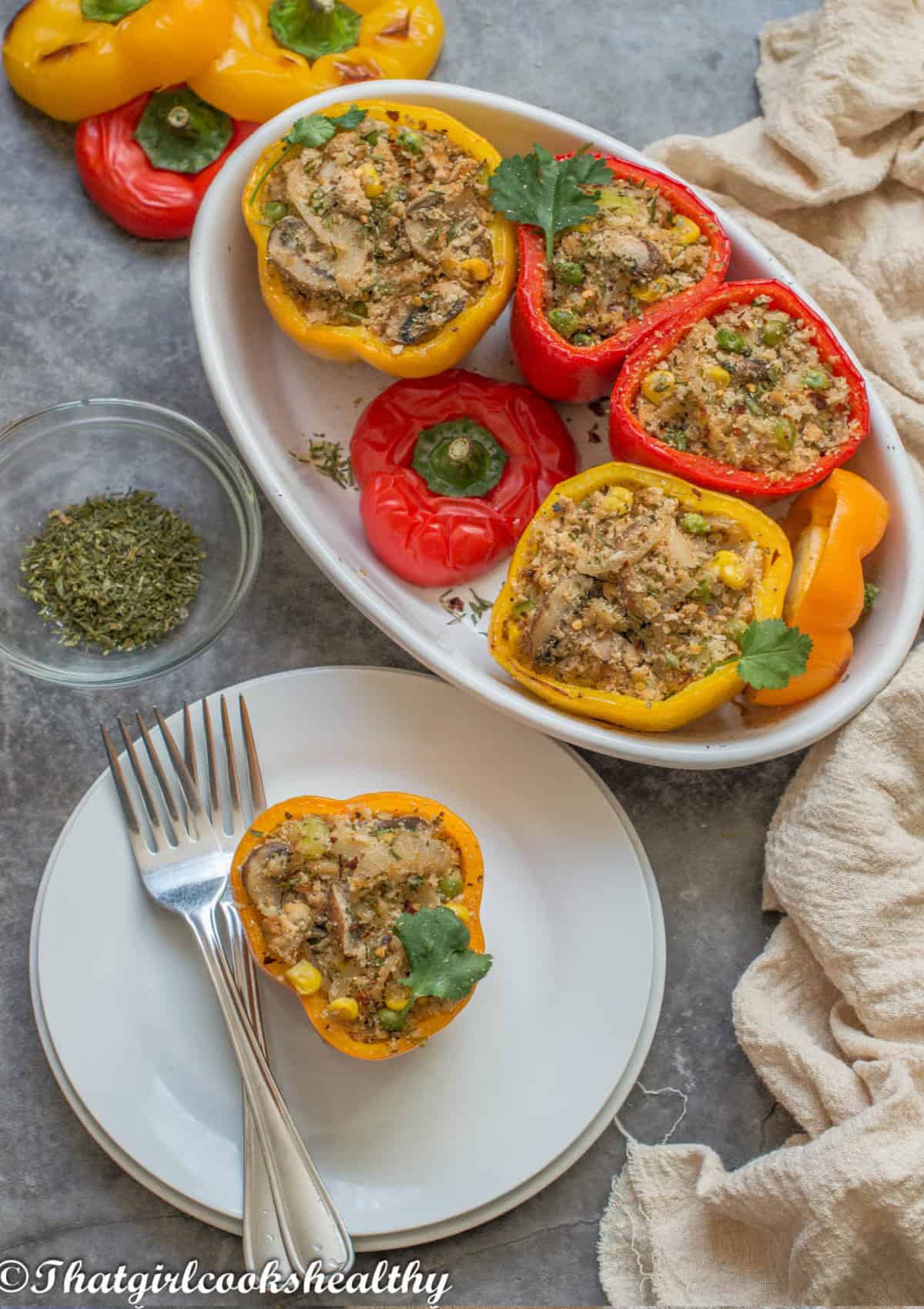4 peppers, stuffed in a dish and one on a white plate with fork