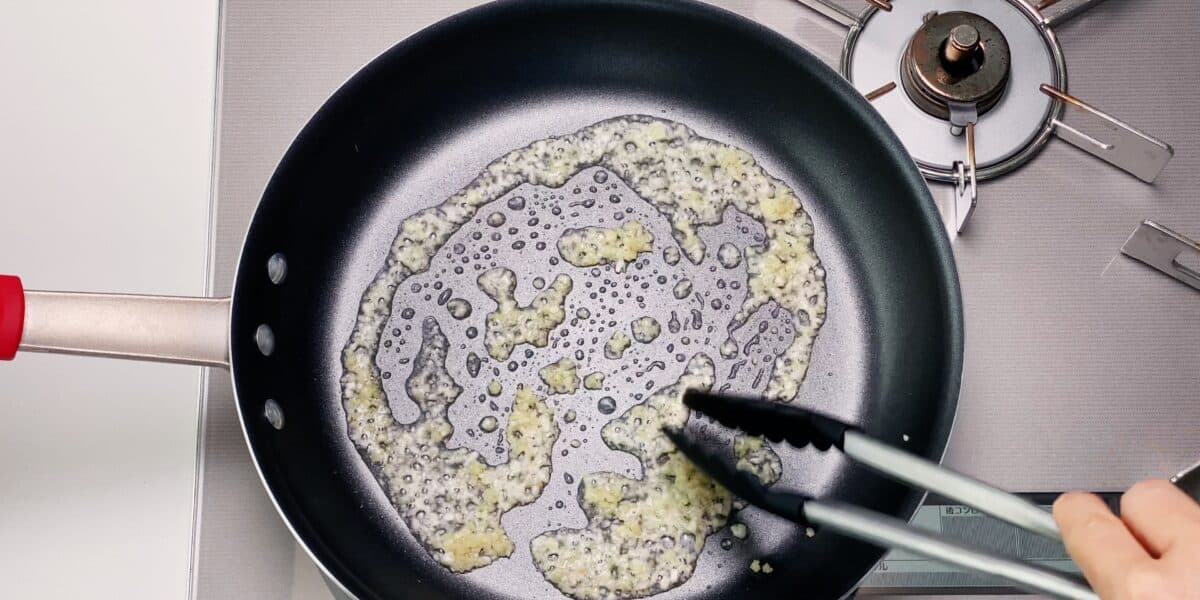 Frying garlic and ginger in a frying pan for making a Chinese stir-fry.