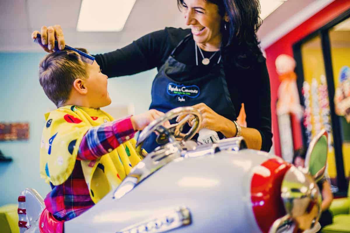 Stylist and client interacting at kids hair salon franchise