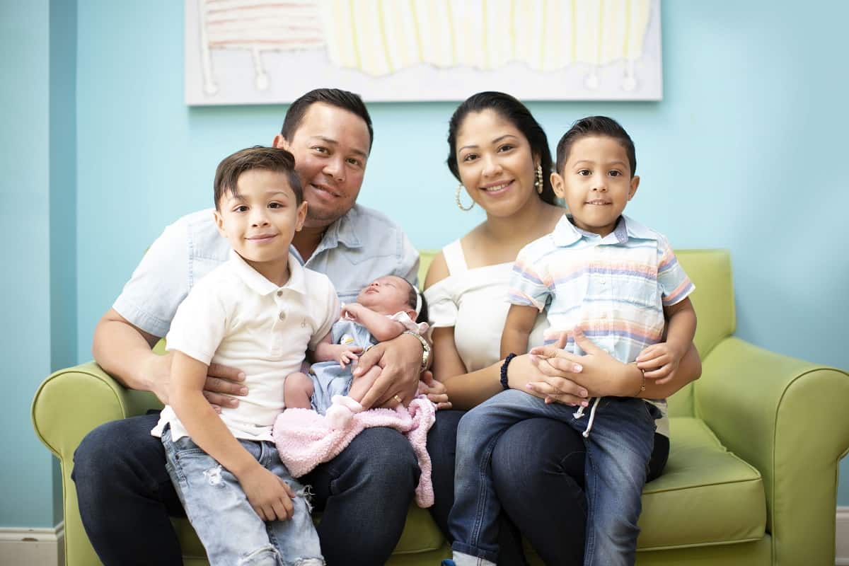 family sitting on a couch at a pigtails & crewcuts kid's hair salon franchise