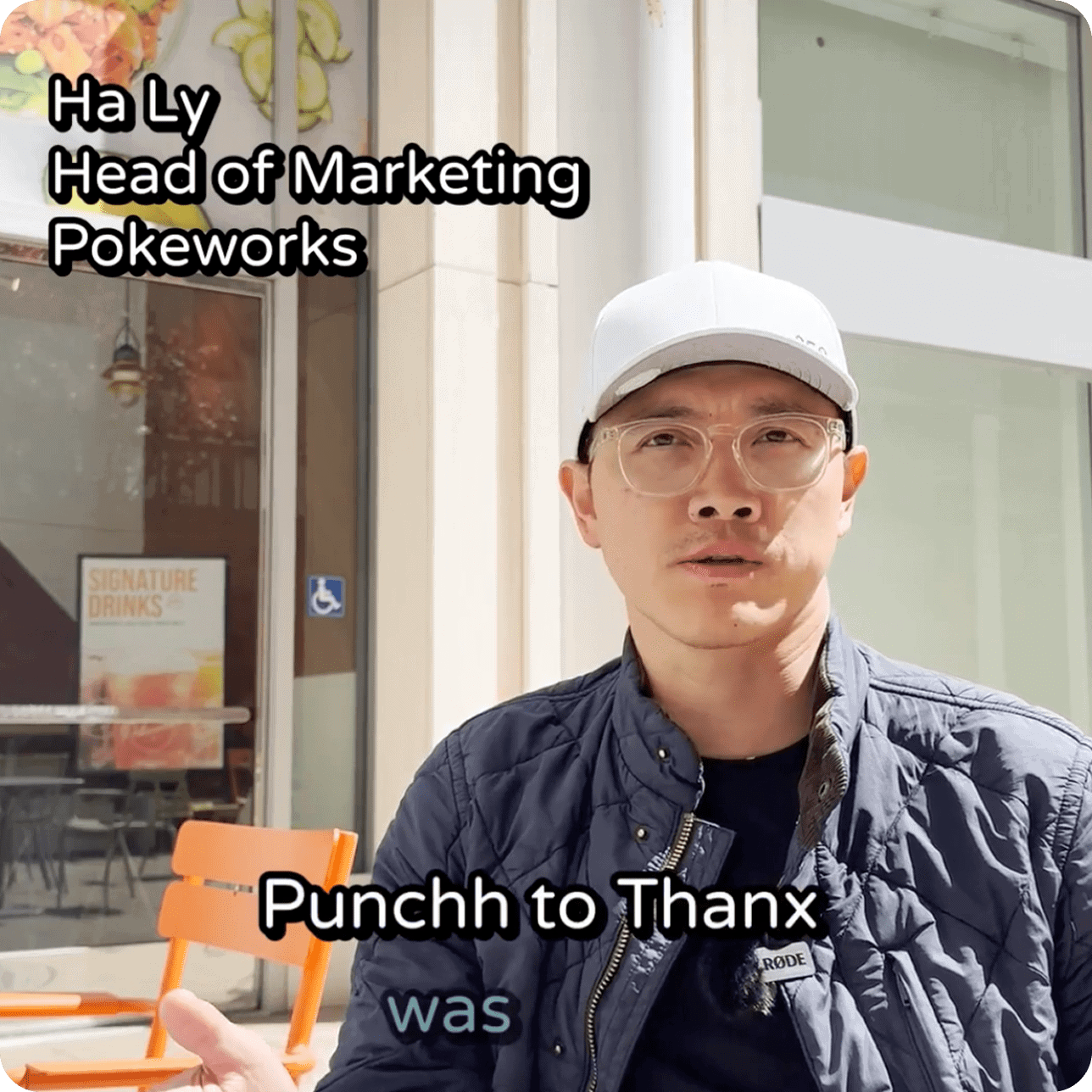 Ha Ly, Head of Marketing at Pokeworks, speaking in an outdoor video interview. He is wearing glasses, a white cap, and a dark jacket. Text on screen reads: ‘Punchh to Thanx was’ with a restaurant window and orange chairs in the background.