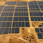 Vista aérea de planta fotovoltaica desde cenital con instalación solar de múltiples hectáreas documentada en 4K