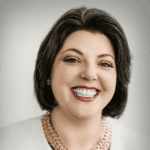 A woman with short, dark hair smiles at the camera