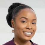 A woman with dark hair pulled into an updo wearing a dark shirt