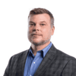 A man wearing a dark blazer and blue dress shirt.