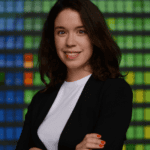 A woman with dark hair wearing a white blouse and black blazer.