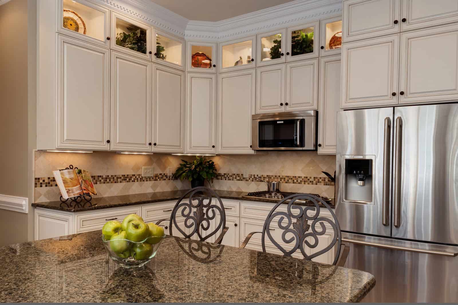 a traditional kitchen with the combo of glazed white cabinets and tropic brown granite