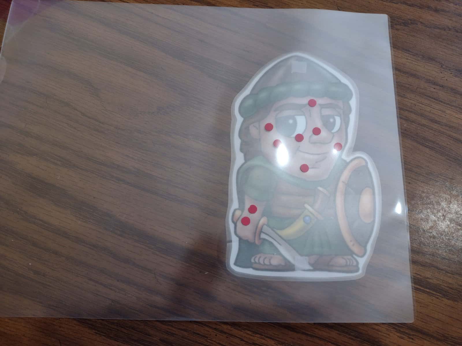 Picture of red dots on a closed laminating pouch on a picture of Naaman