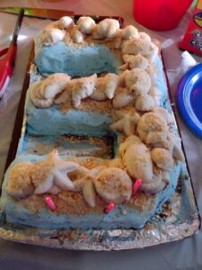 Picture of a beach themed ice cream cake with seashells on top