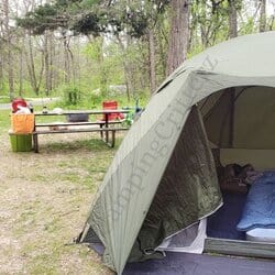 foreground shows a Marmot Limestone 6p tent with air mattress and moving blankets inside. middle ground shows a picnic table with a coleman fold n go stove, propane cylinder and goal zero lantern. Background shows camp chairs near a fire ring